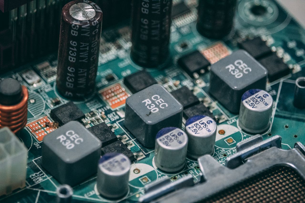 Home Detailed view of electronic components on a circuit board showcasing capacitors and semiconductors.