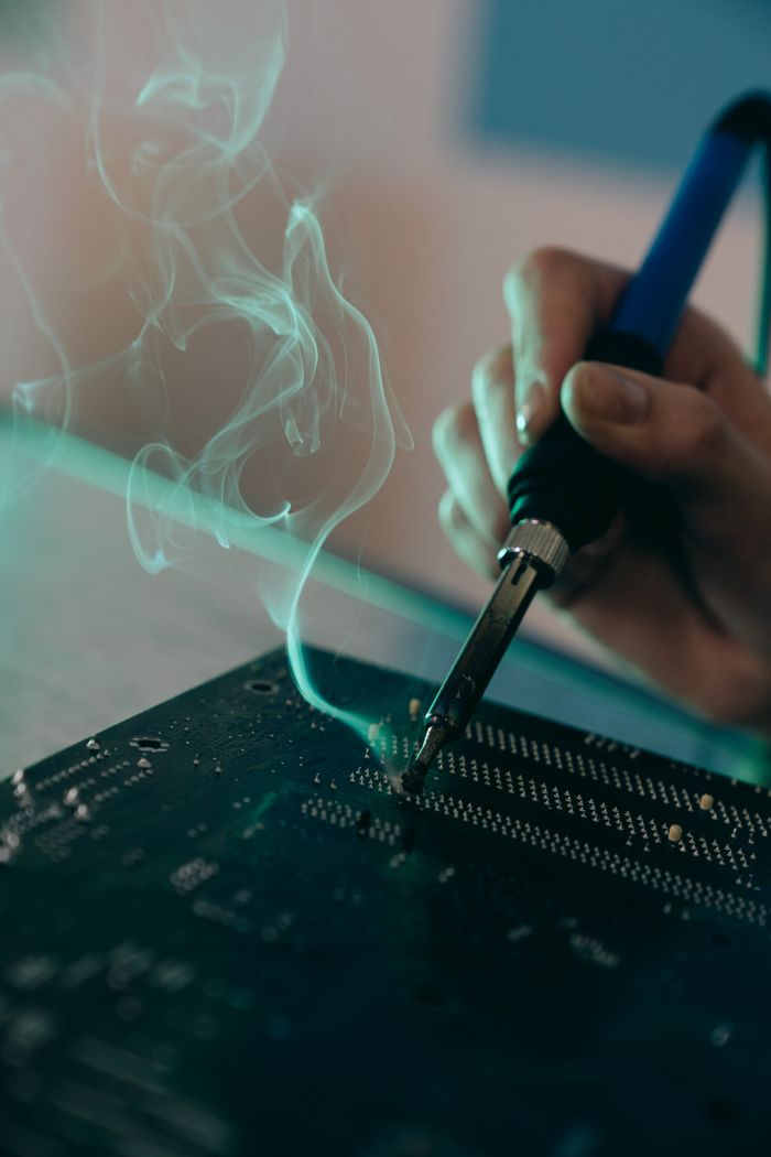 Home Detailed view of a person soldering a circuit board, capturing technology and engineering concepts.